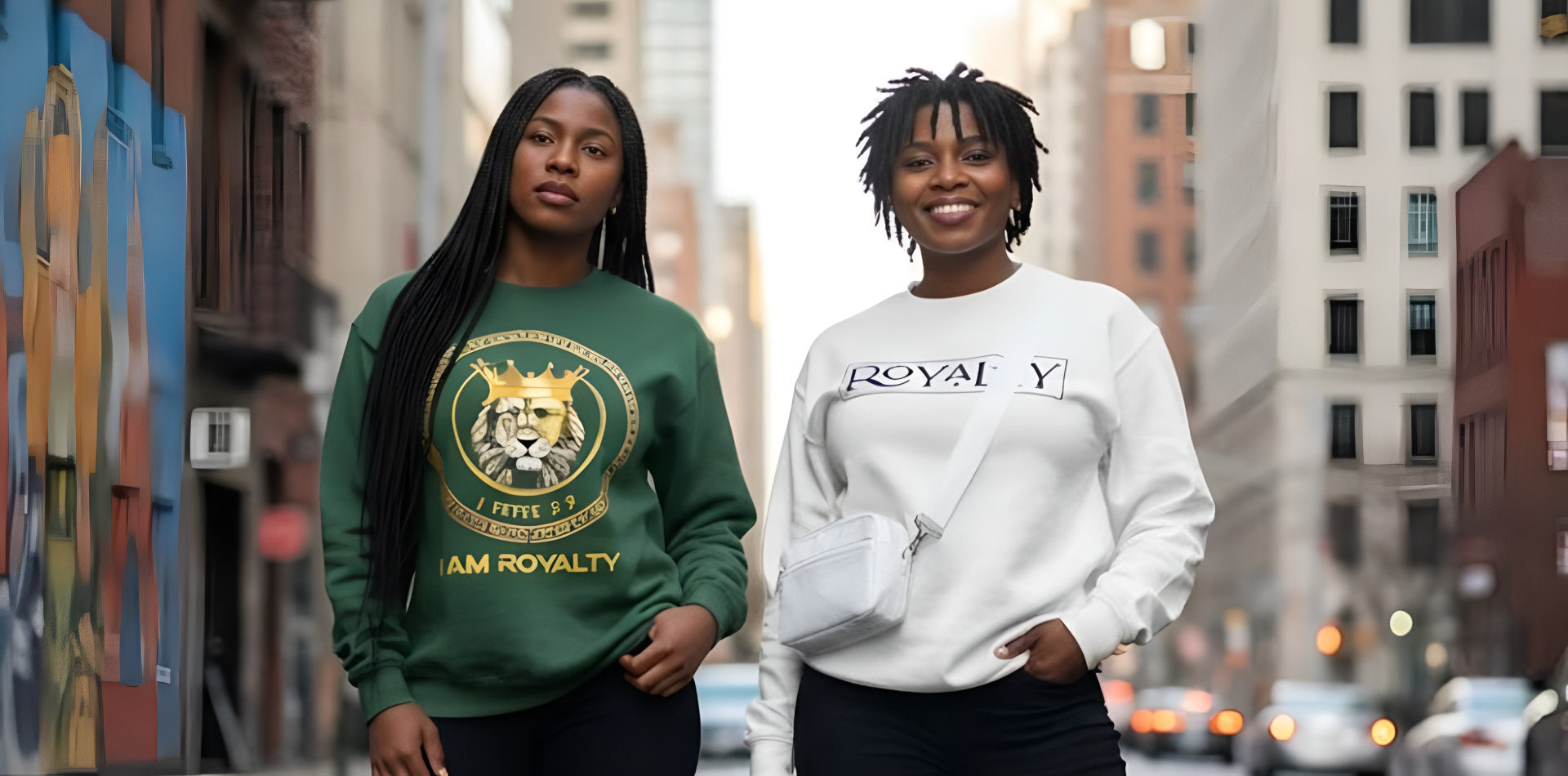 Two women wearing Royalty themed sweatshirts walk confidently down a city street, showcasing urban fashion.