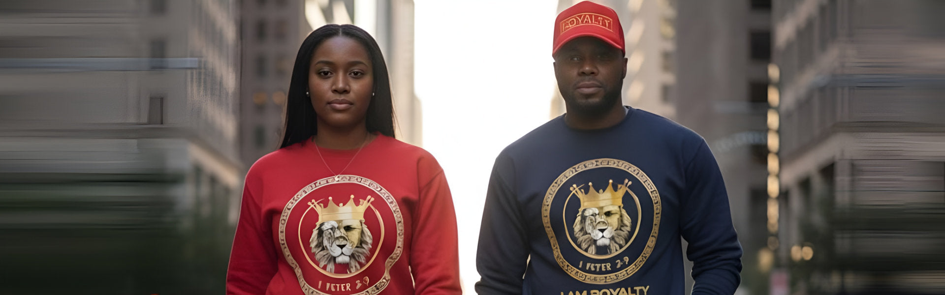 Two individuals wearing matching sweatshirts with a crowned lion logo and I AM ROYALTY text, walking in an urban setting.
