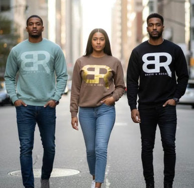 Three individuals wearing Brave & Regal branded sweatshirts walk confidently down a city street, showcasing casual fashion.